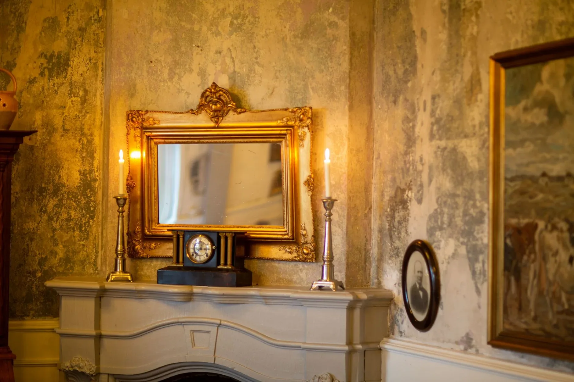 A classic interior scene featuring a golden mirror, lit candles, and antique decor on a mantel.