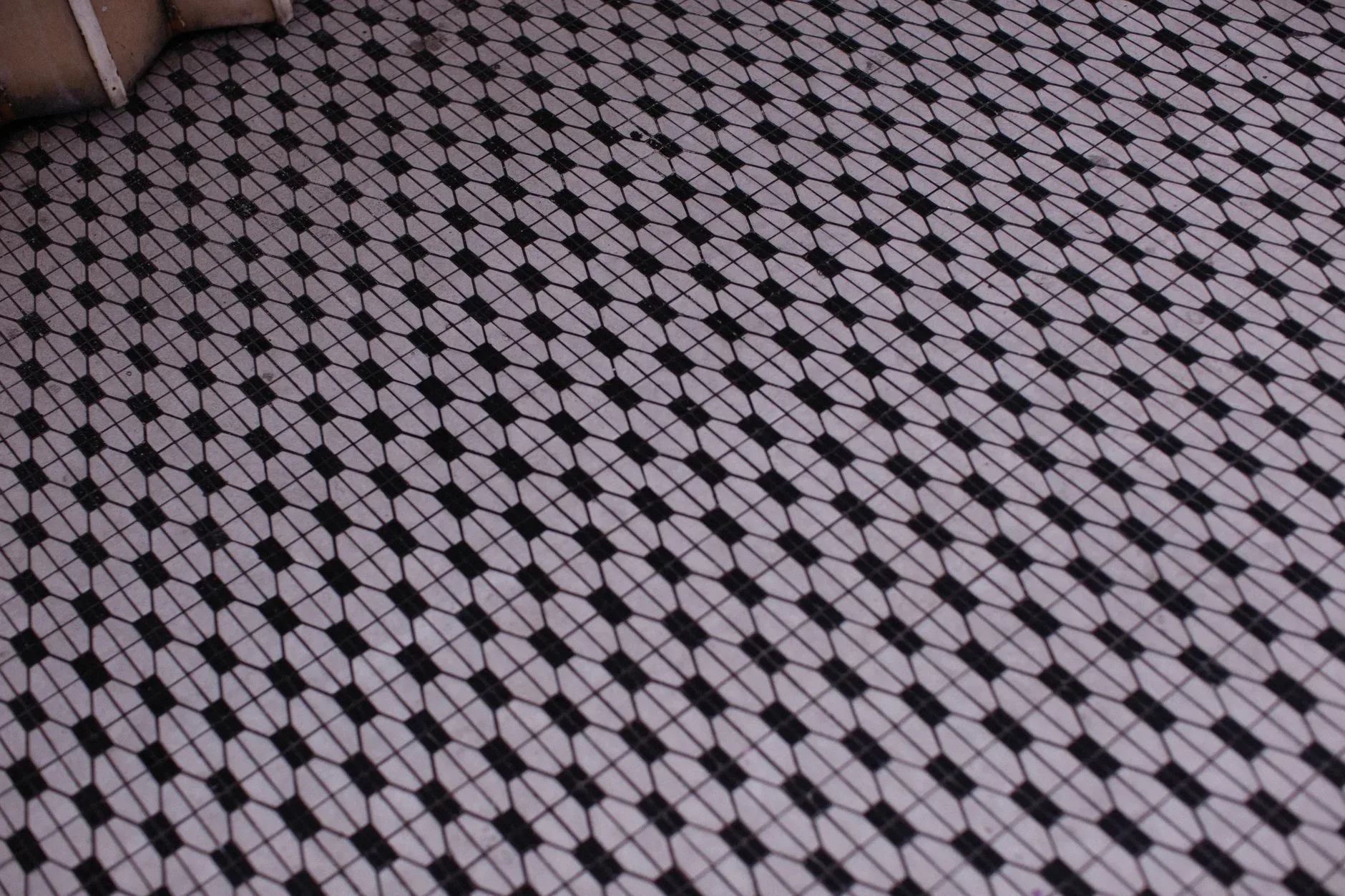 A detailed view of a vintage geometric mosaic tile floor with a retro pattern.