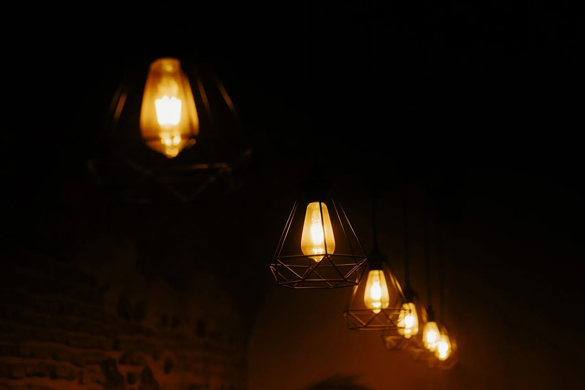A row of vintage pendant lights casting a warm glow in a dimly lit environment.