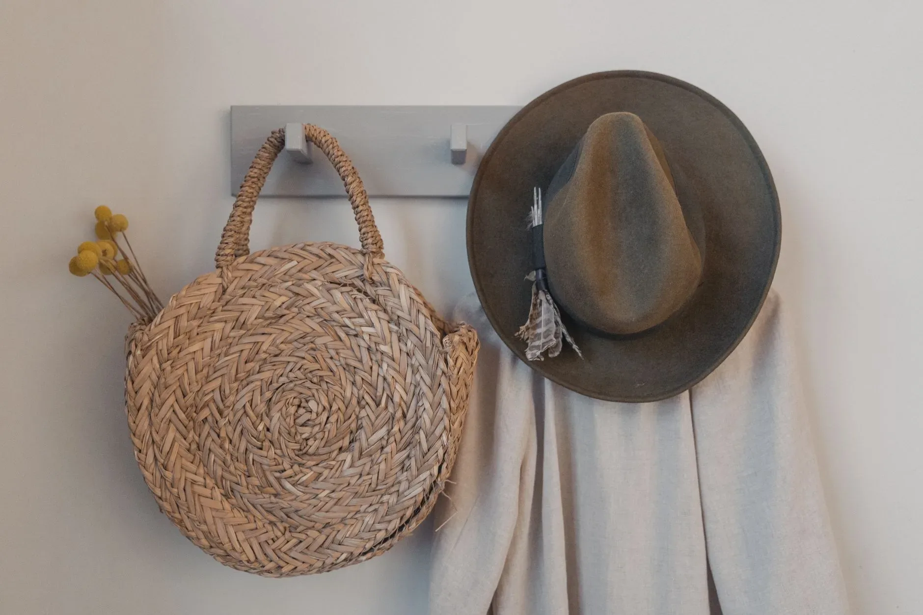 A rustic woven bag and hat hanging on a peg, showcasing minimalist interior decor.