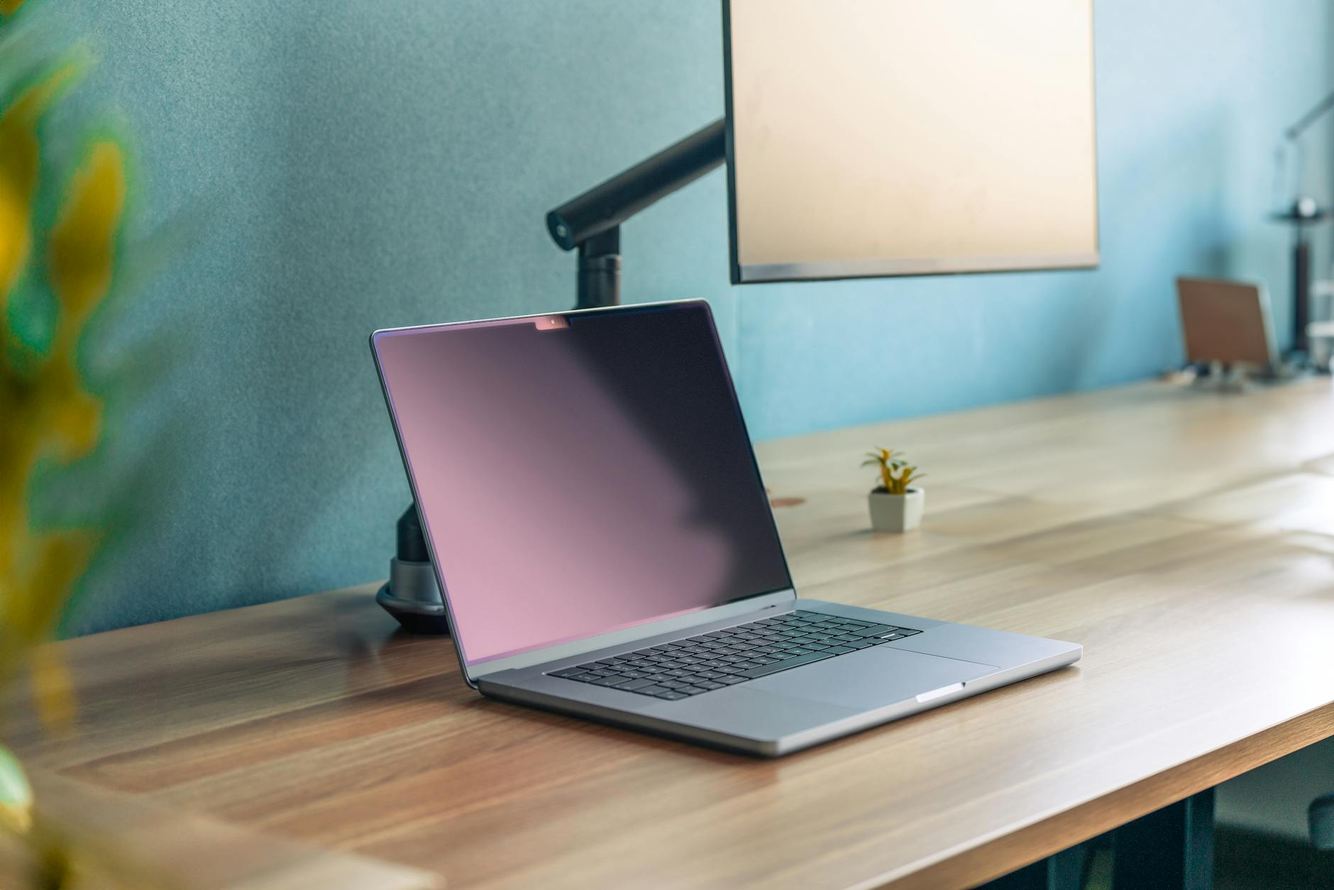 A sleek laptop on a wooden desk with a minimalist aesthetic in a modern office setting.