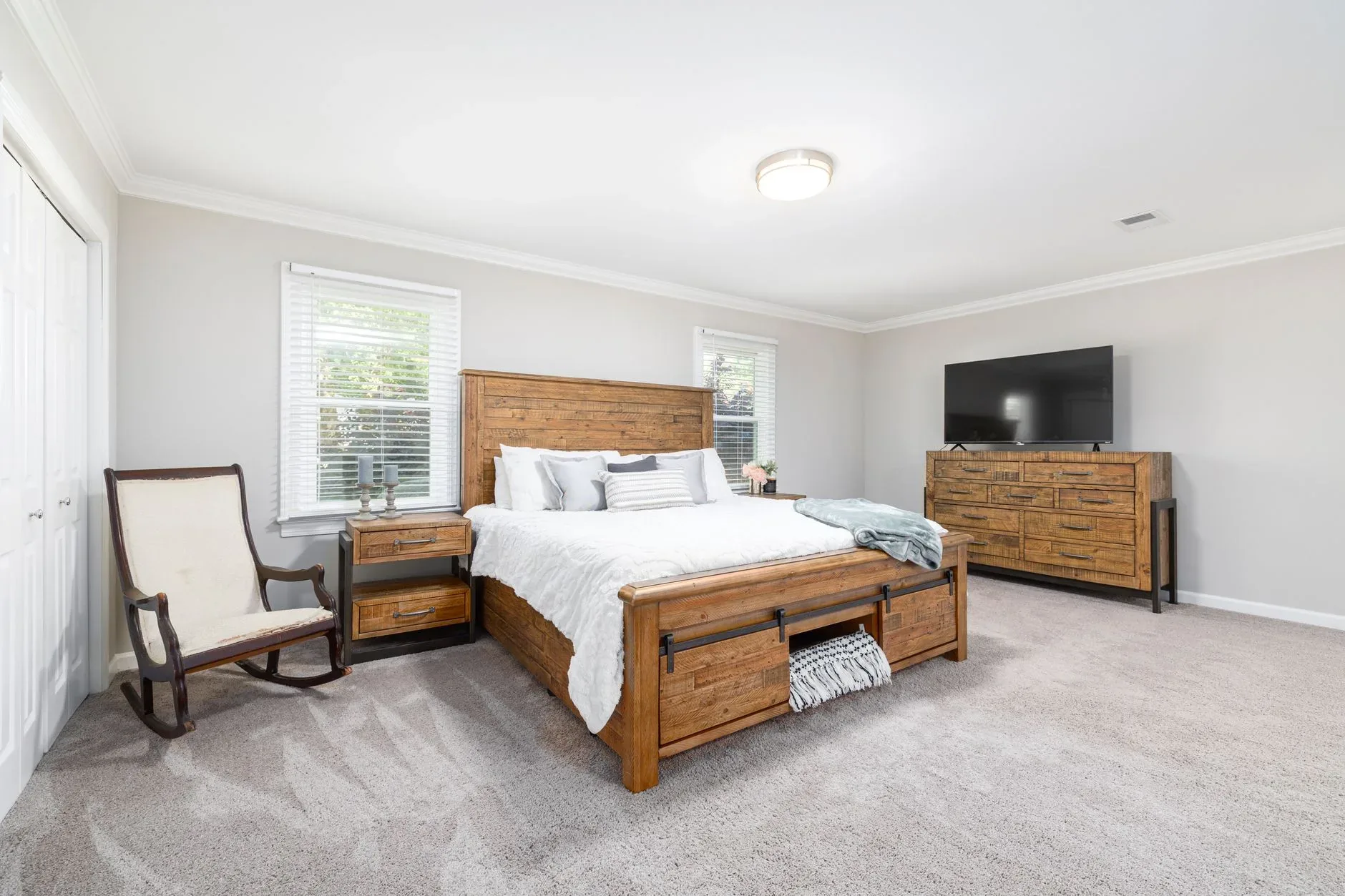 A spacious and cozy bedroom featuring wooden furniture and modern decor.