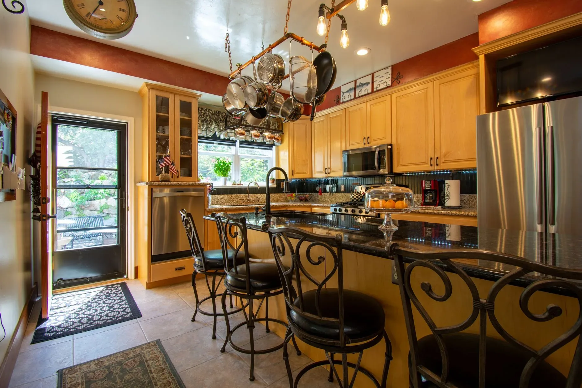 A stylish kitchen featuring granite countertops, bar stools, and stainless steel appliances.