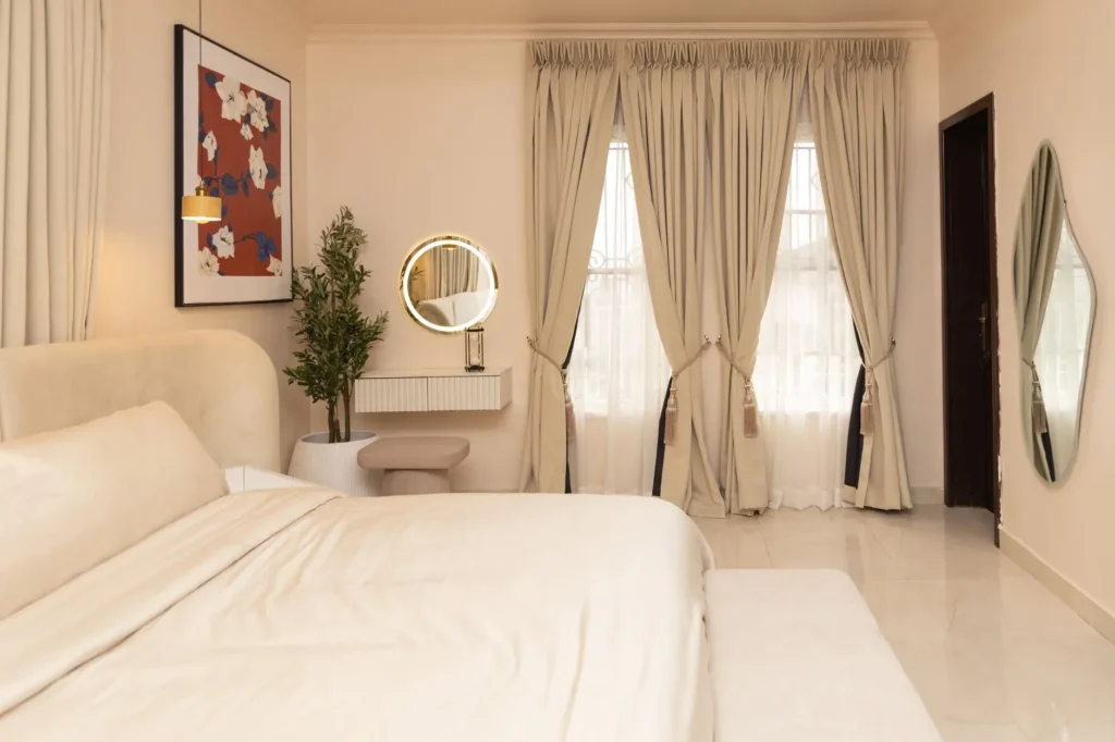 A stylish, modern bedroom with soft colors, large windows, and elegant decor.