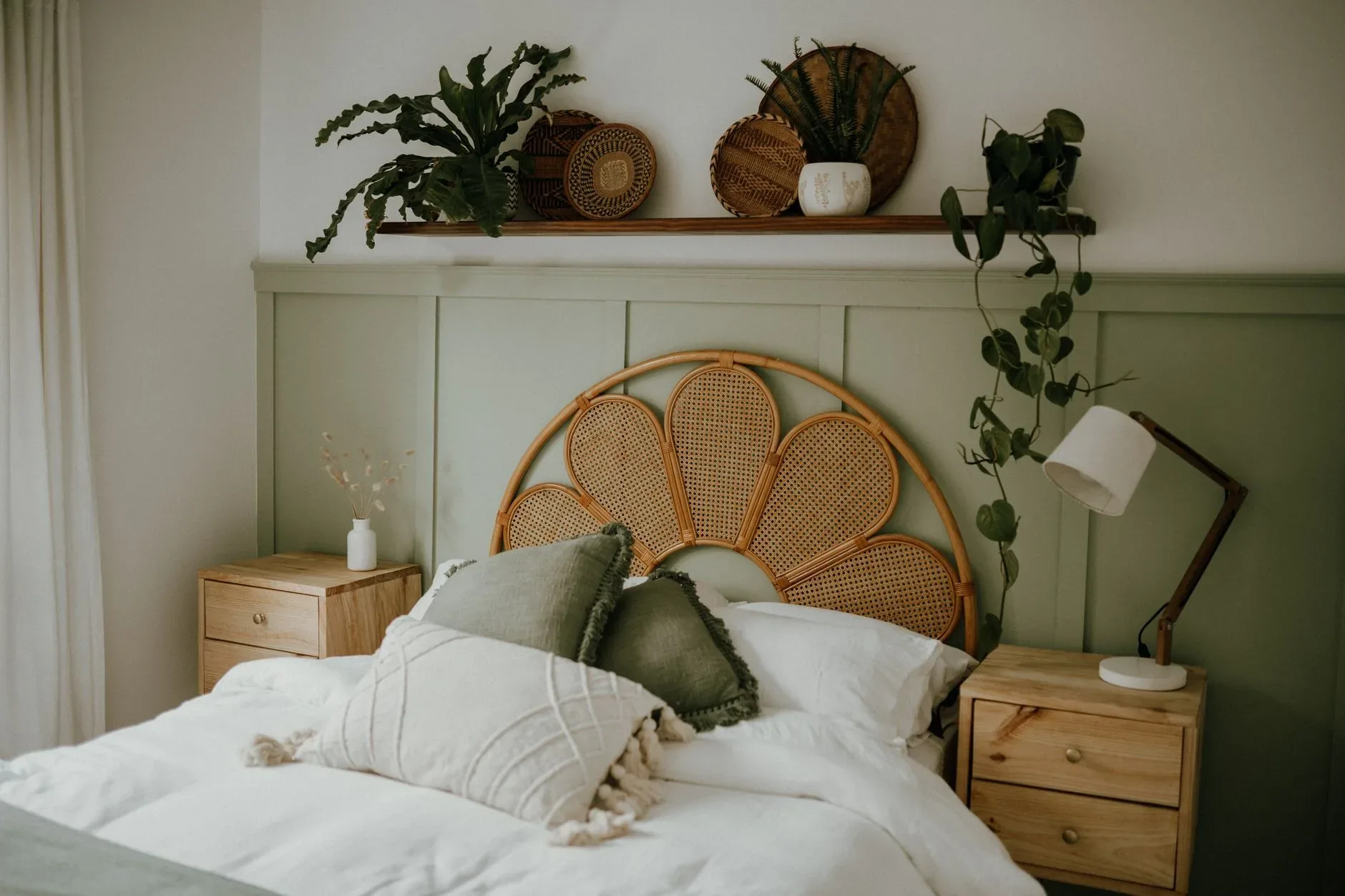 A warm Scandinavian bedroom featuring natural wicker decor and lush green plants.