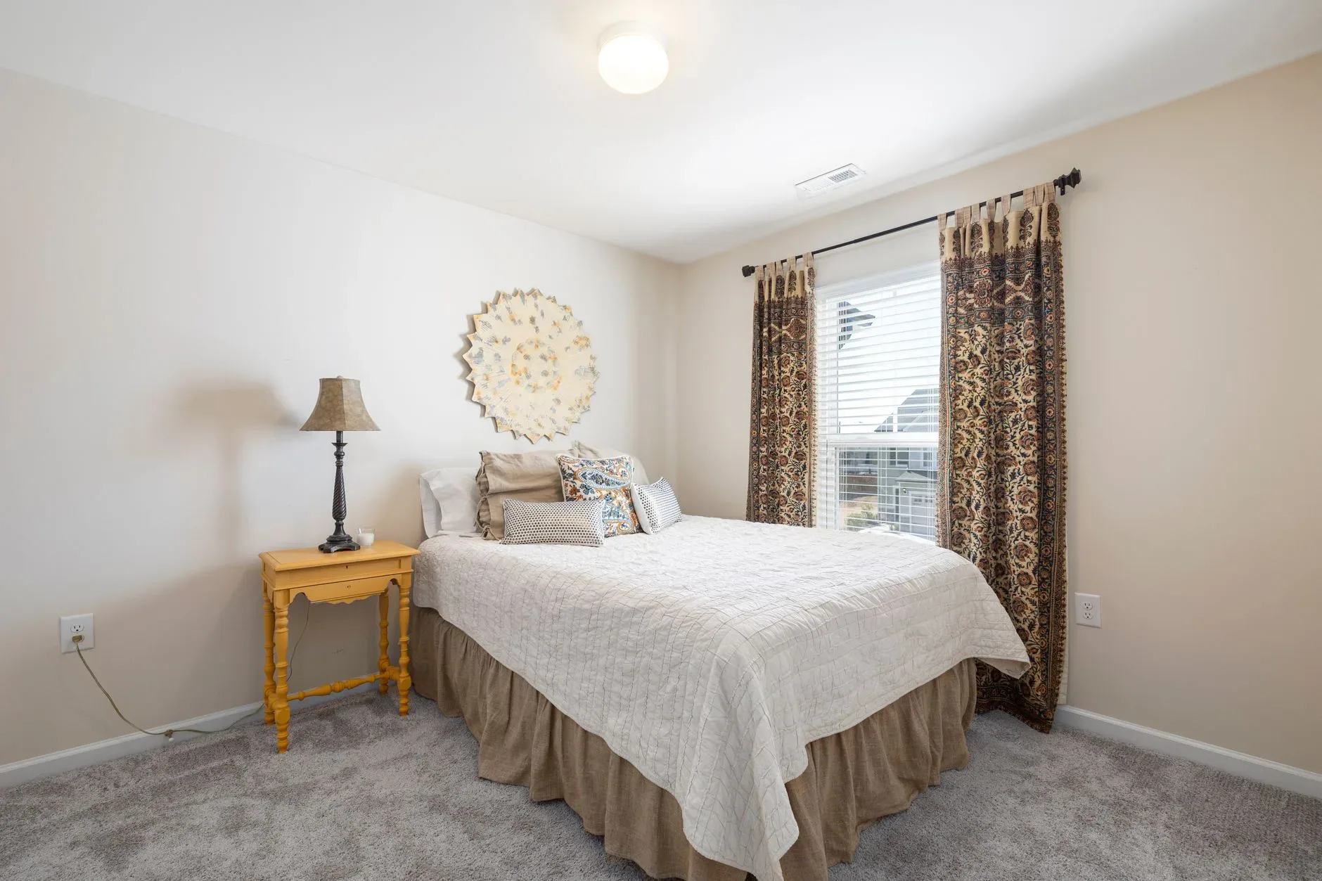 A well-decorated bedroom with a comfortable bed, decorative pillows, and natural light streaming in.