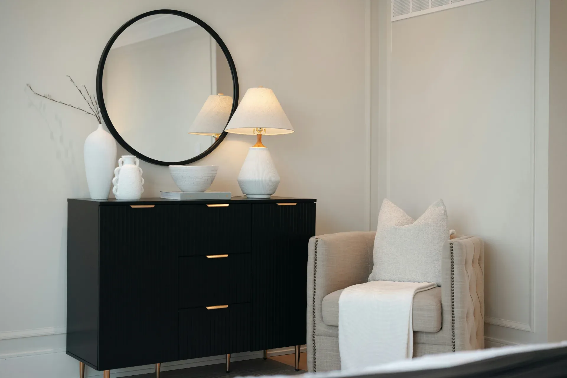 Black dresser with mirror and chair in a bedroom