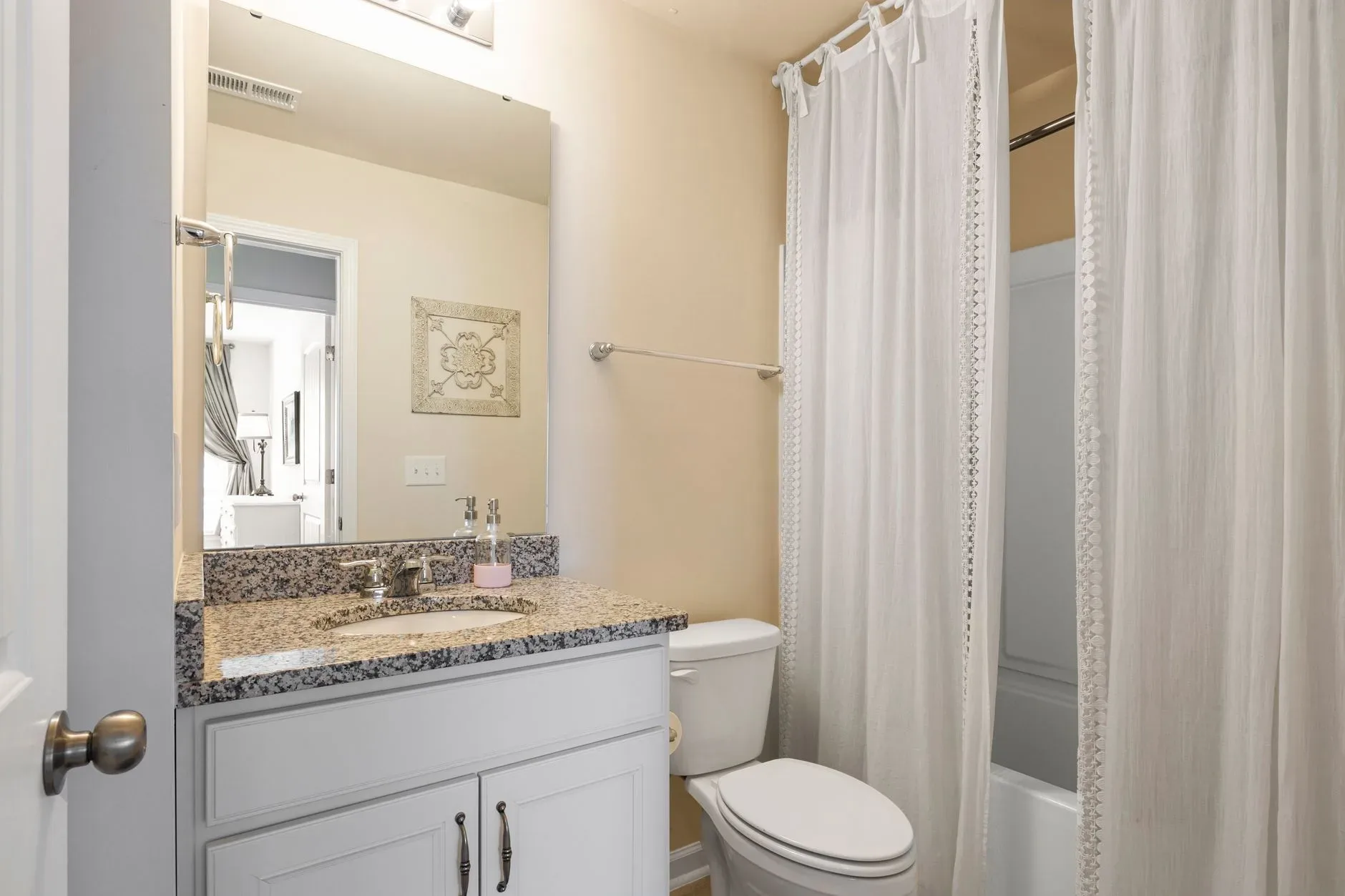 Bright and clean bathroom featuring a granite countertop and shower area.