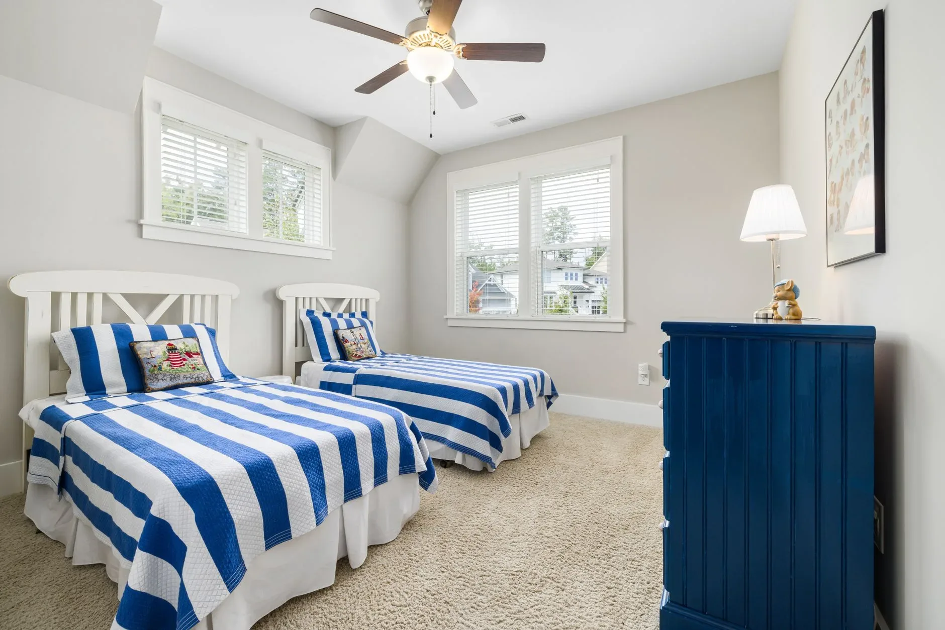 Bright and cozy kids\' bedroom featuring twin beds with blue striped bedding and elegant decor.