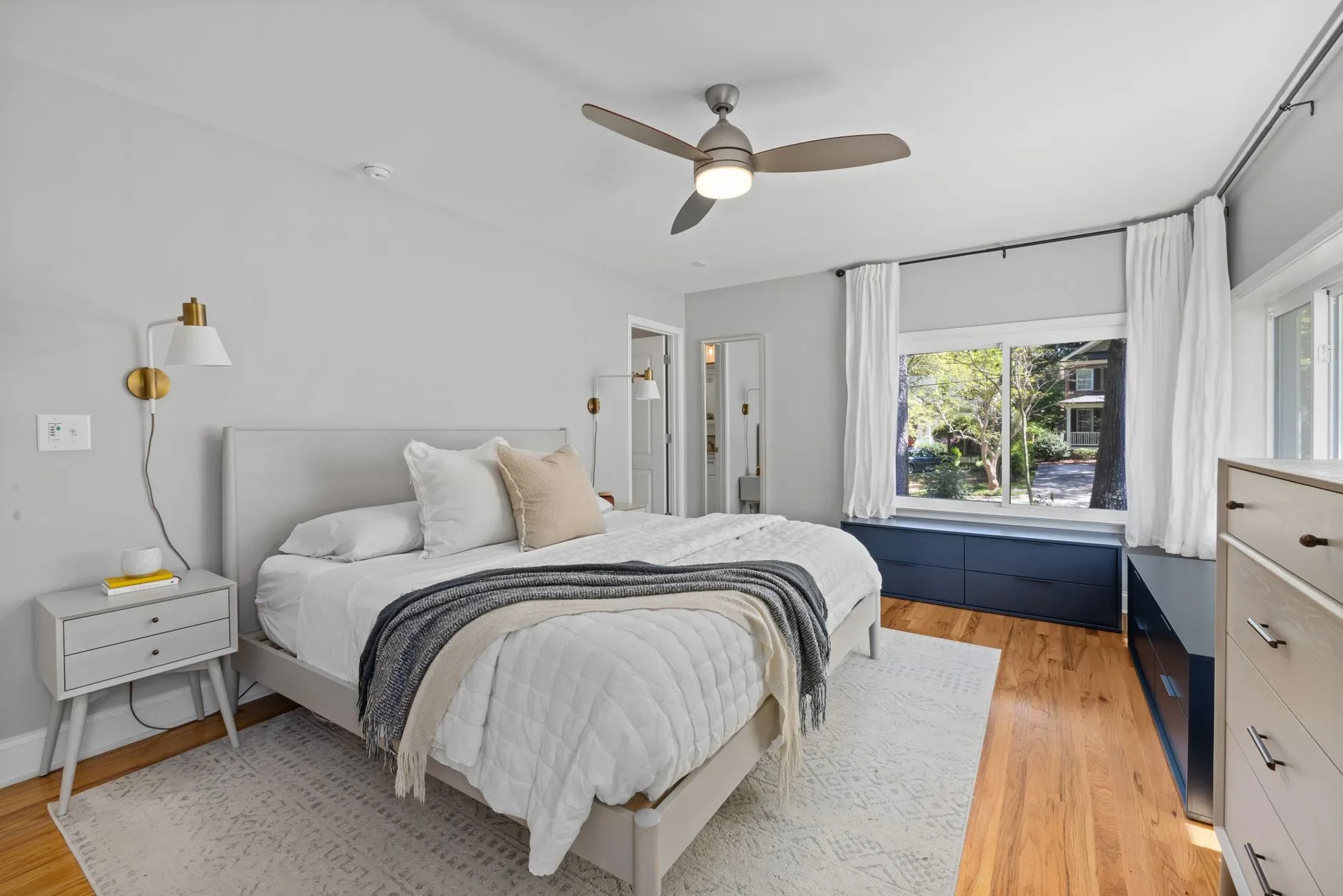 Bright and cozy modern bedroom featuring a minimalistic design with large windows and wooden flooring.