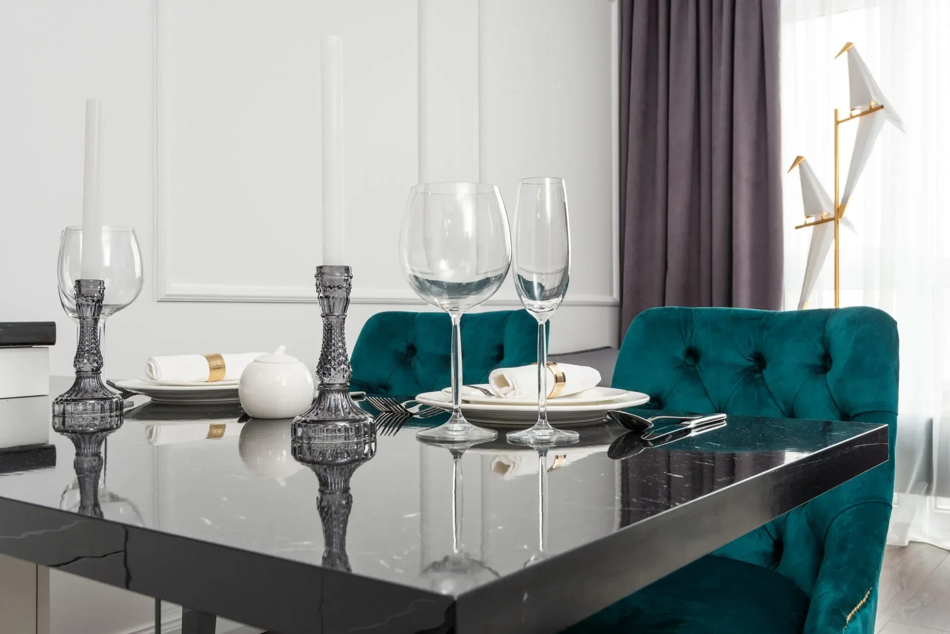 Chic dining room with green chairs, marble table, and elegant tableware setup.