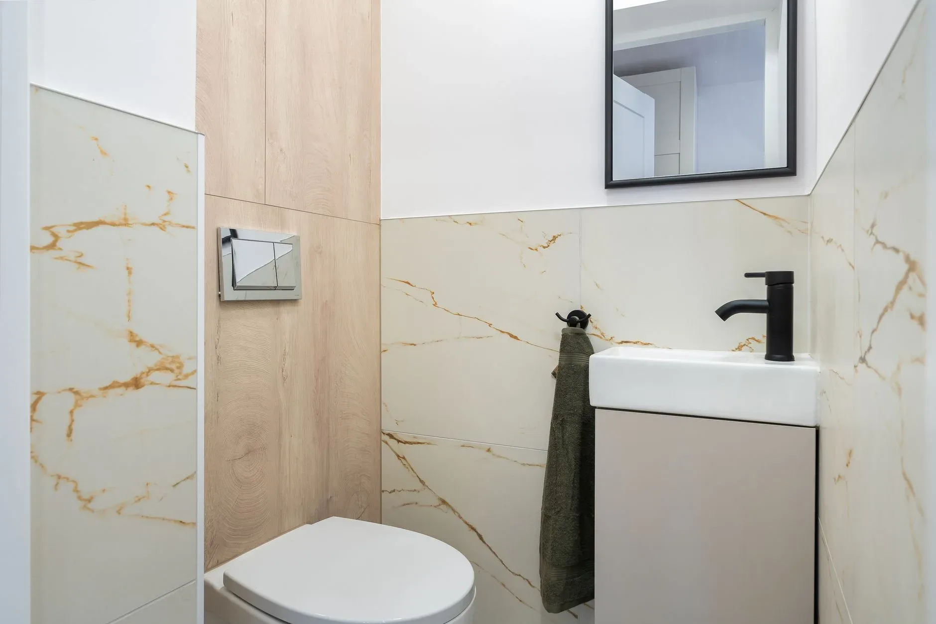 Clean and stylish modern bathroom with marble tiles and a small sink.