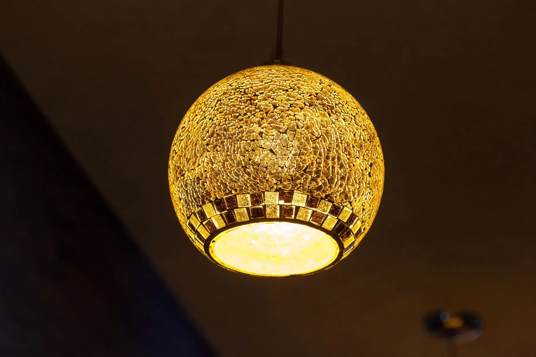 Close-up of an illuminated mosaic pendant lamp indoors, adding warmth and style to interior design.