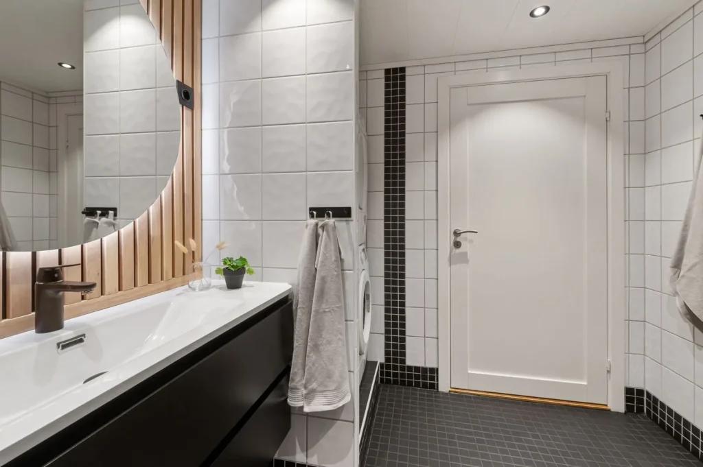 Contemporary bathroom featuring a large mirror, sleek sink, and minimalist decor in neutral tones.