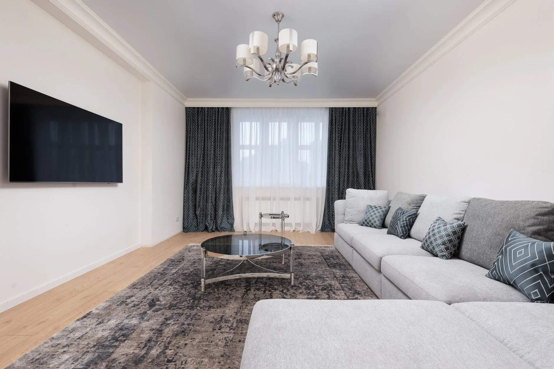 Contemporary living room with decorative cushions on sofa against table and TV with black screen in house