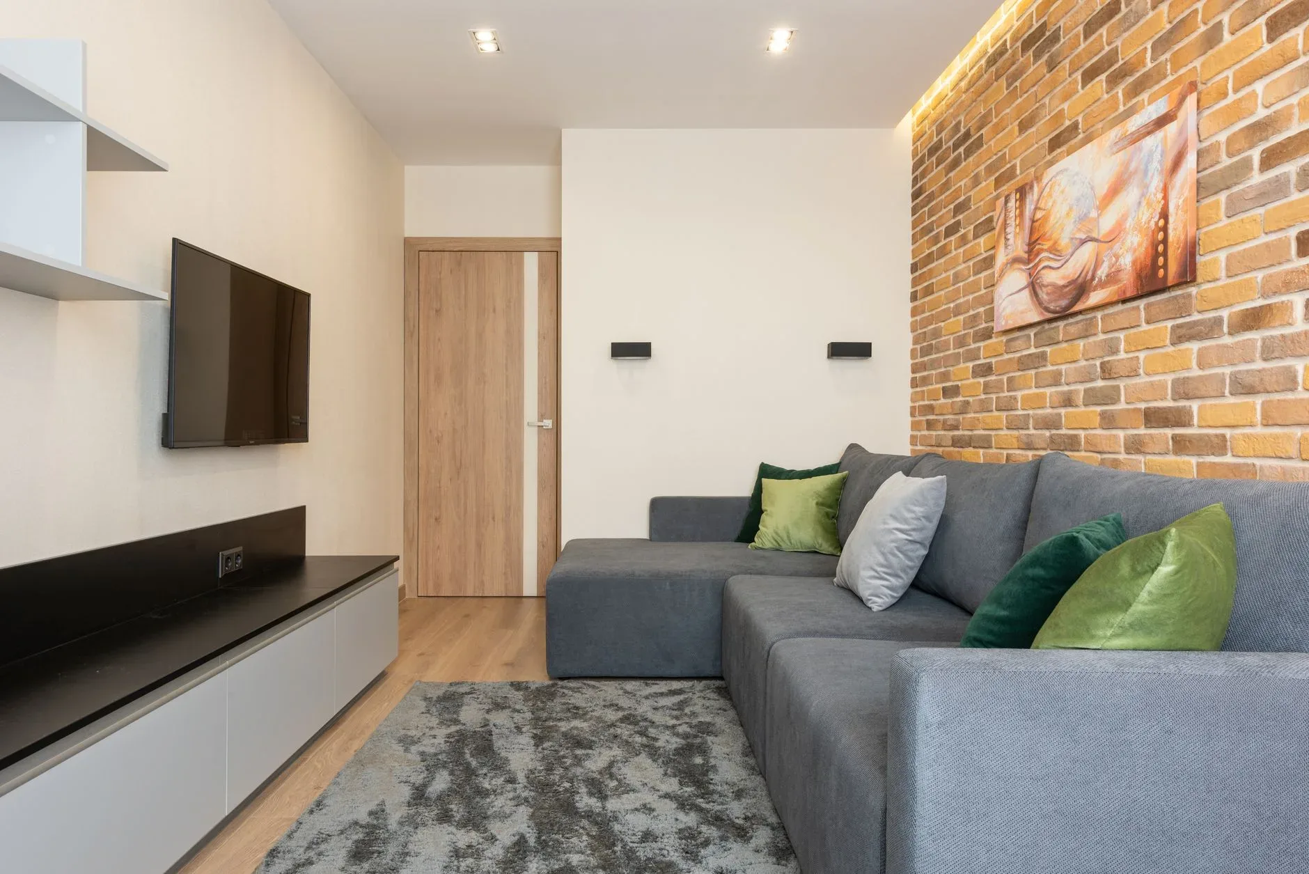 Cozy modern living room with brick wall and gray sofa, perfect for relaxation.