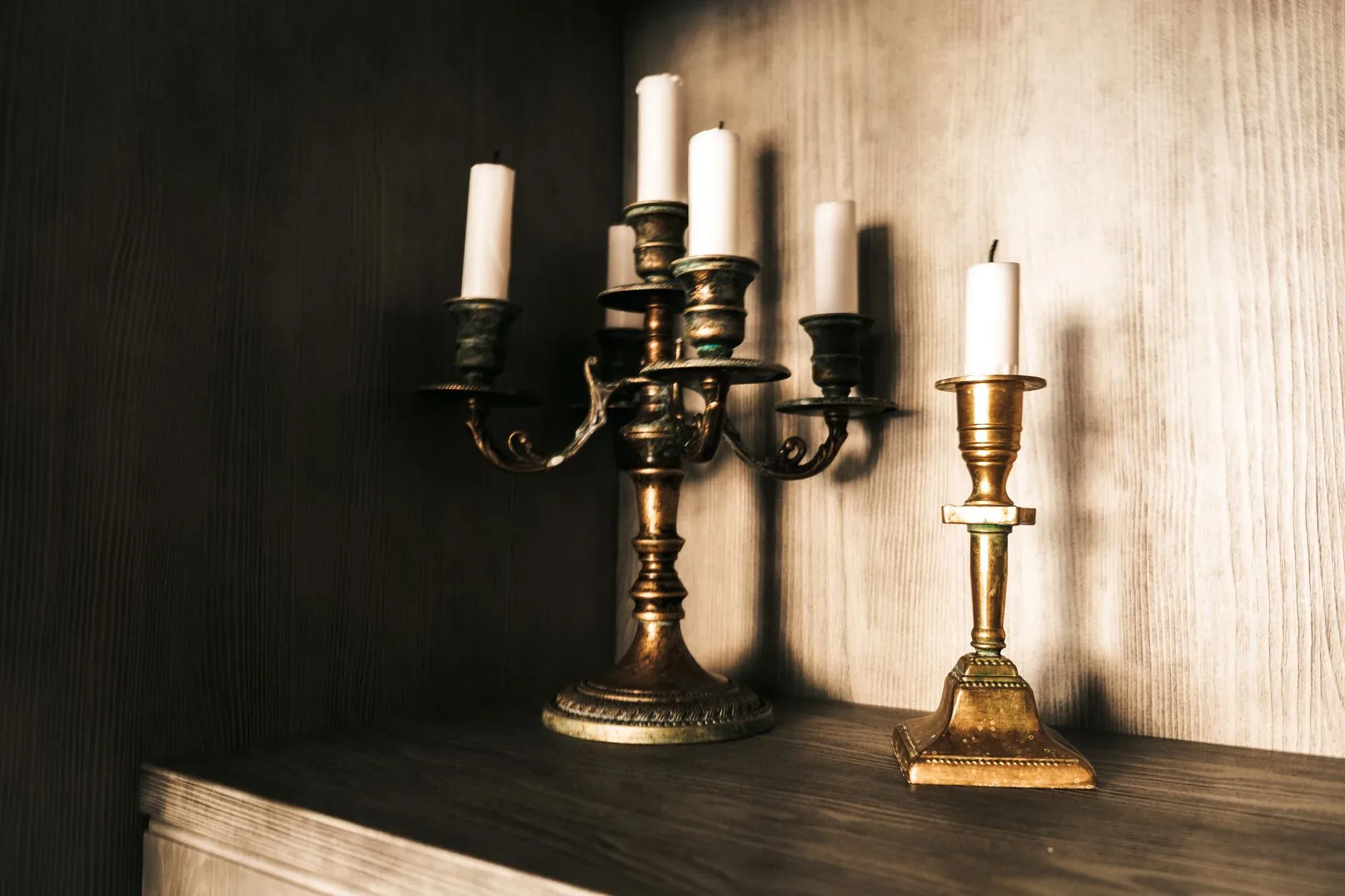 Elegant arrangement of vintage brass candlesticks with candles on a wooden surface, evoking a classic ambiance.