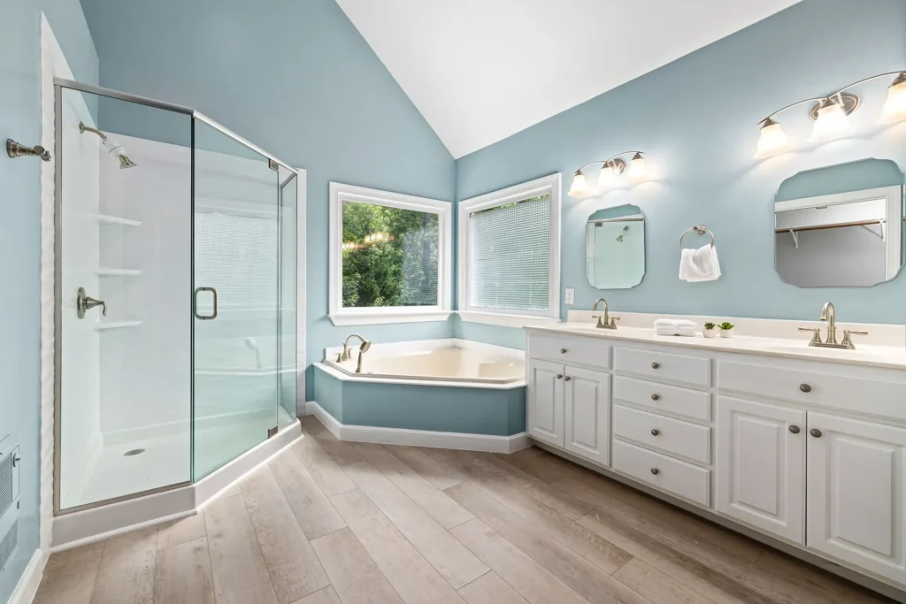 Elegant bathroom interior featuring a glass shower, bathtub, and dual sink vanity.