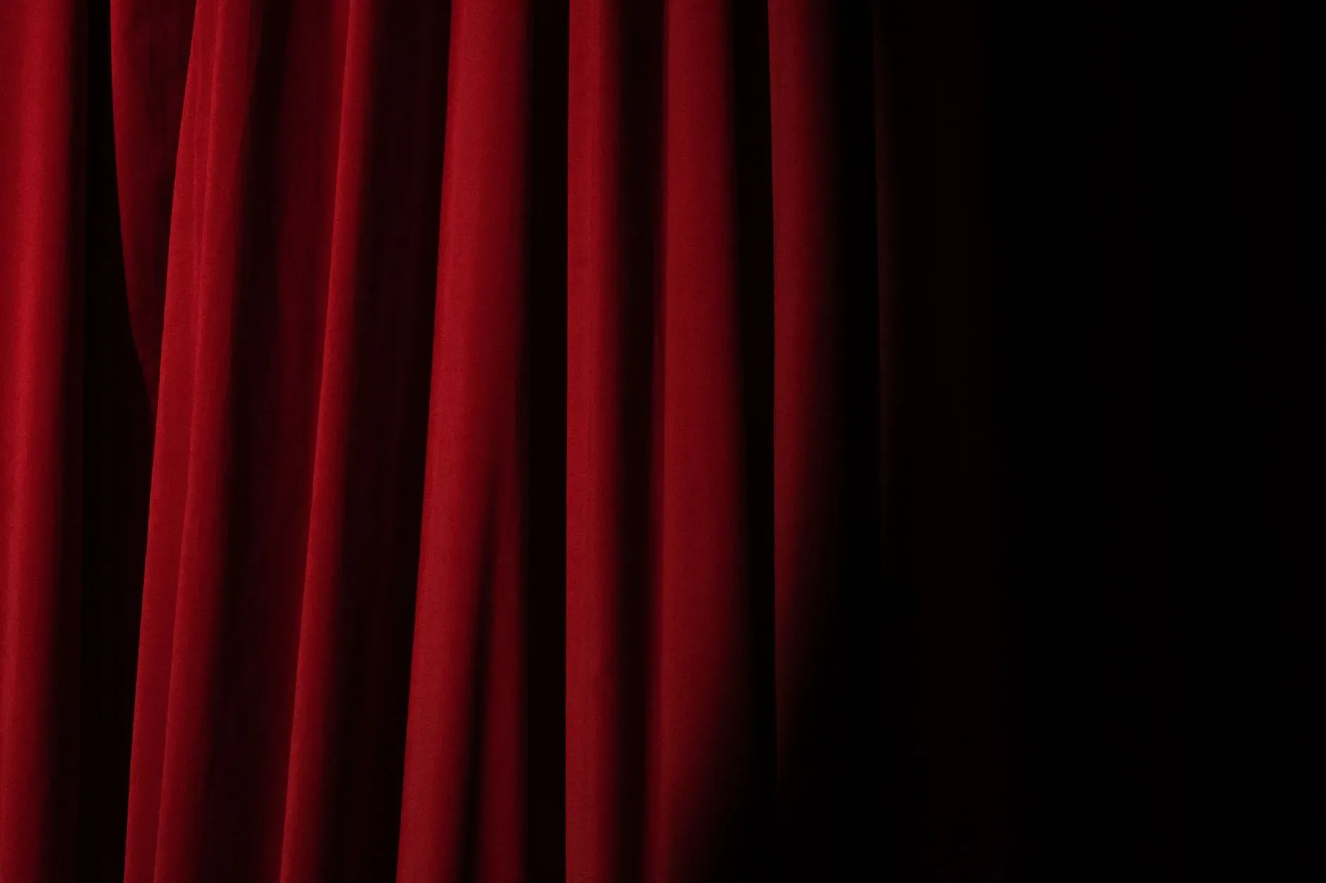 Elegant red velvet curtain with dramatic lighting perfect for theater themes.
