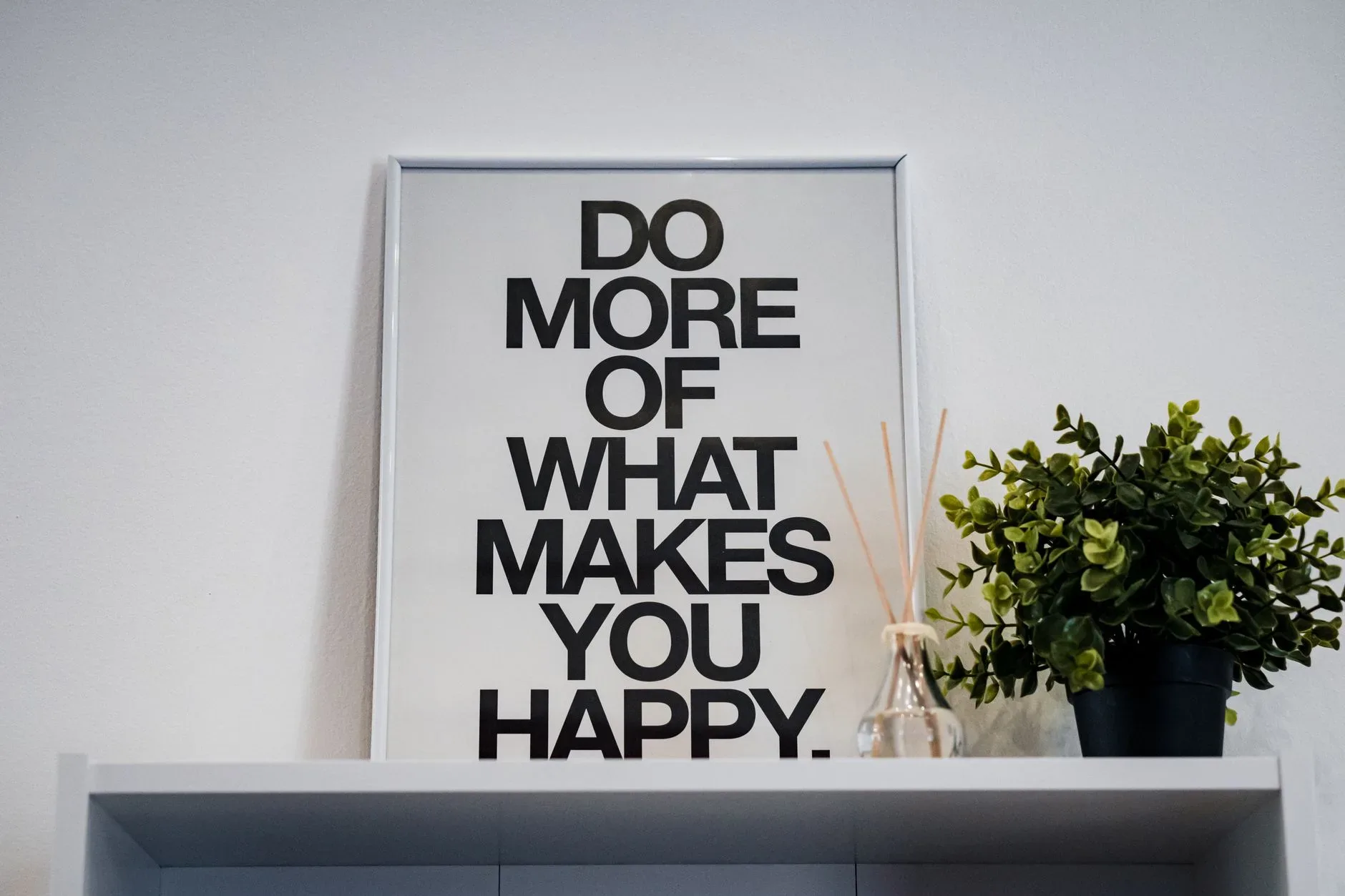 Framed quote \'Do More of What Makes You Happy\' with plant and aroma diffuser.