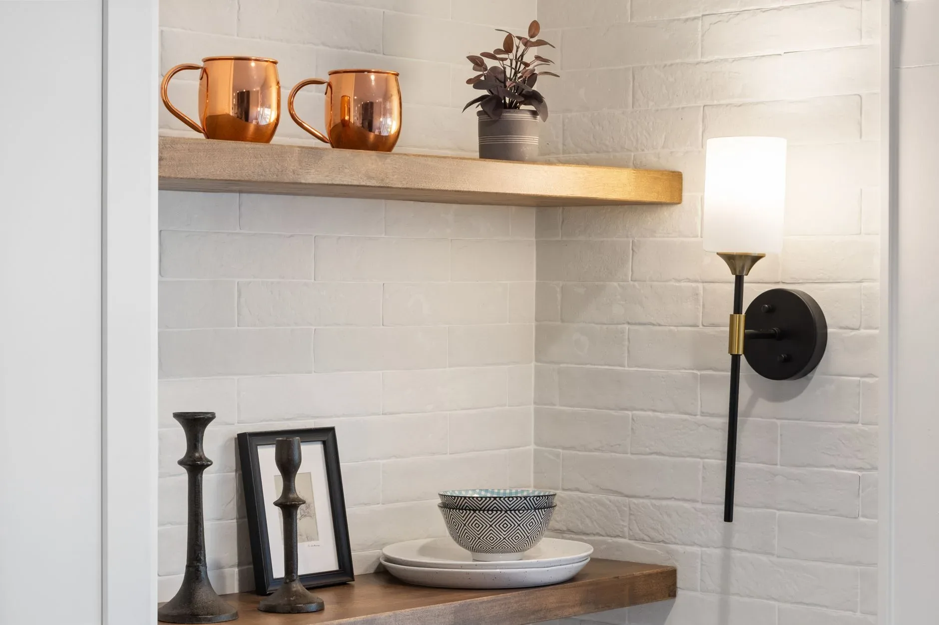 Minimalist interior corner featuring shelves with copper mugs, modern decor, and soft lighting.