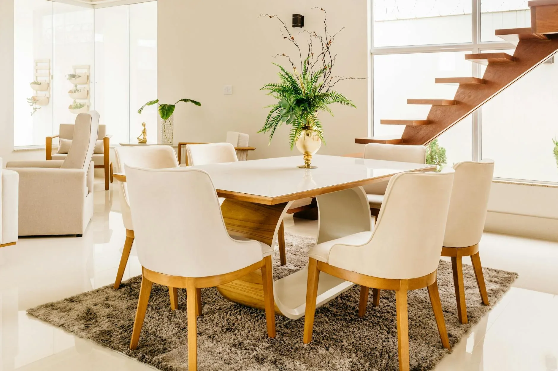 Modern design of light spacious room with stylish wooden table and chairs located near wooden stair in contemporary house