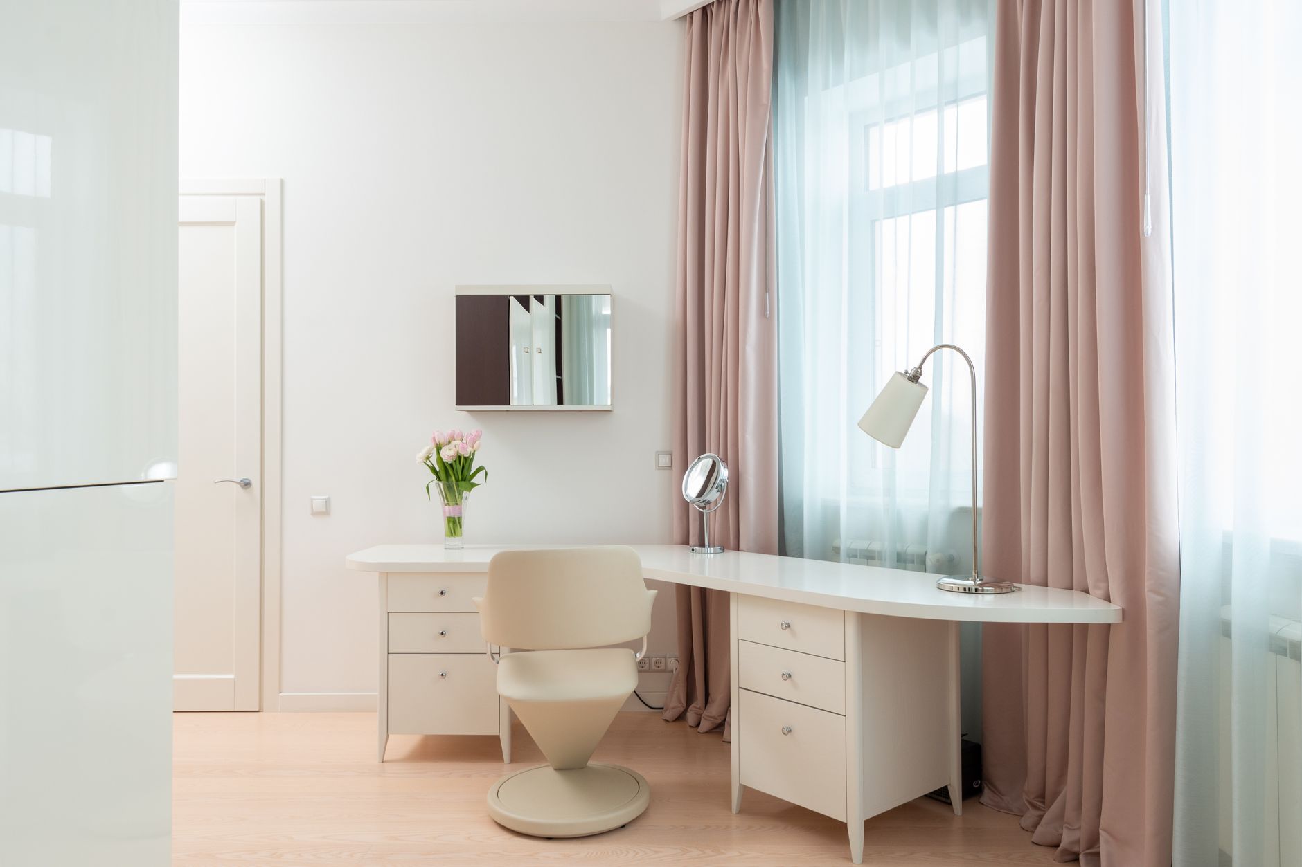 Modern interior of workspace with pink curtains on window and lamp on table