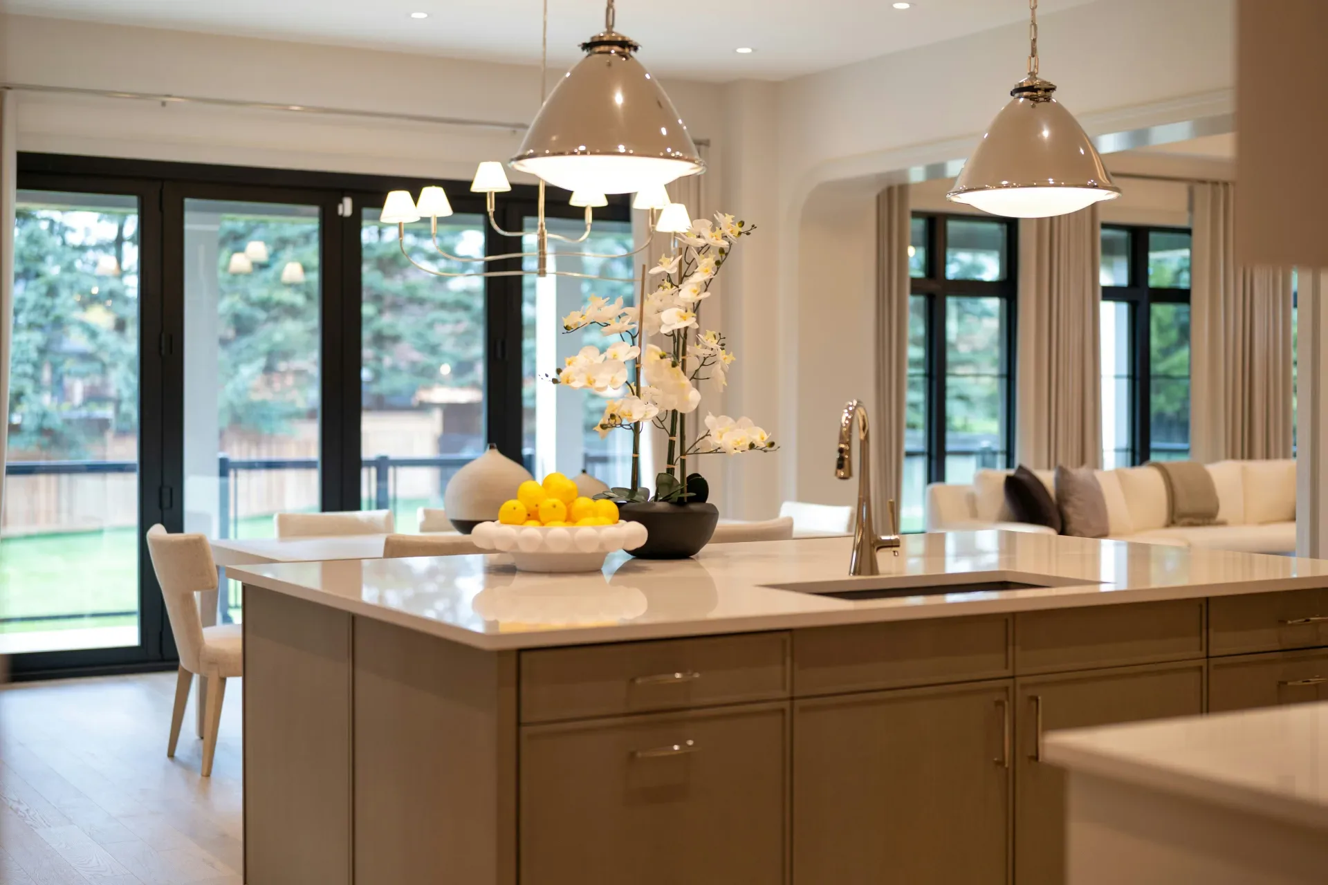Modern kitchen island with sink, pendant lights, and outdoor view.