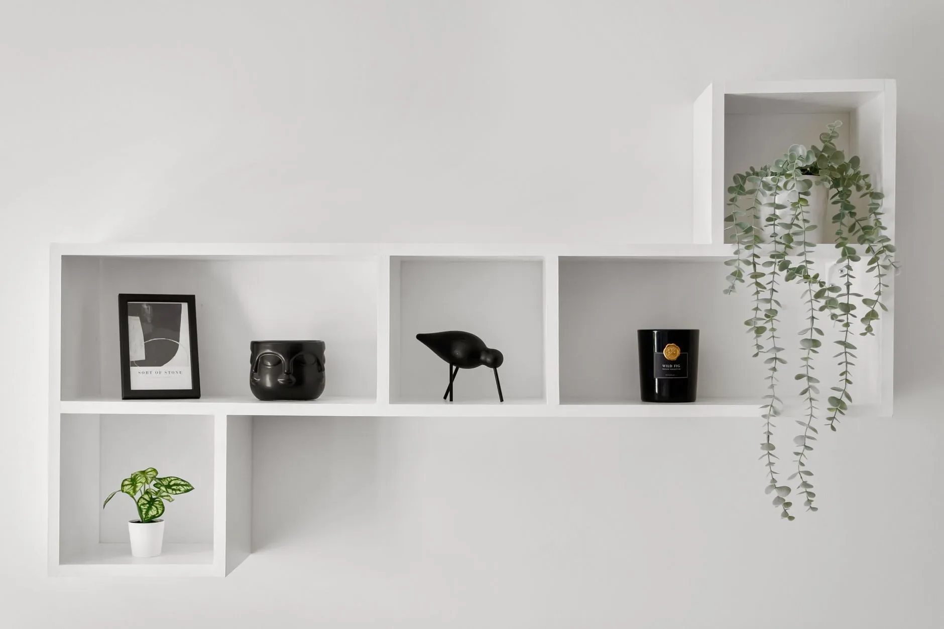 Stylish white wall shelves featuring modern decor and vibrant plants.