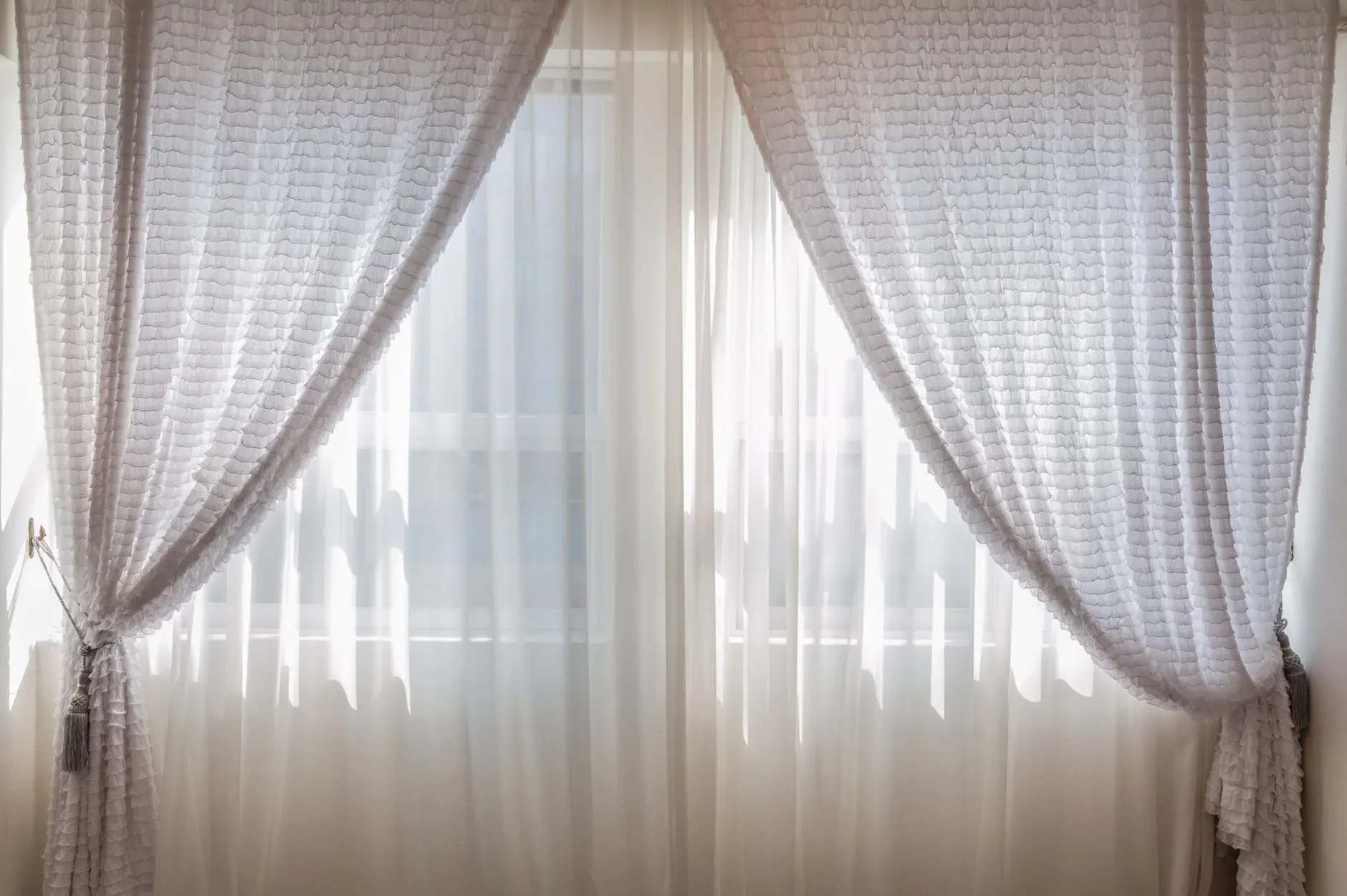 Sun shining through elegant white curtains in a cozy, modern interior setting.