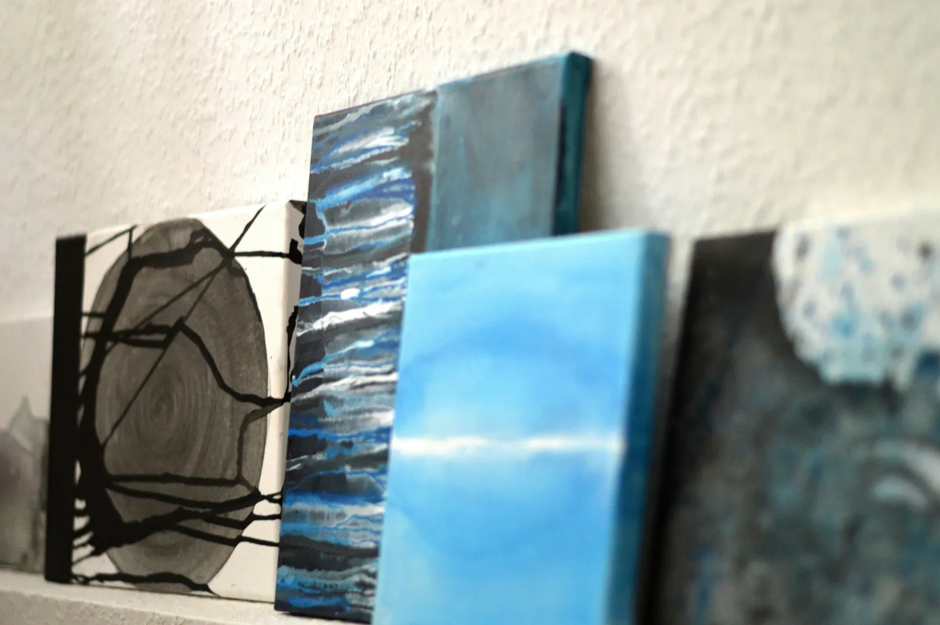Various abstract paintings with blue and black hues.