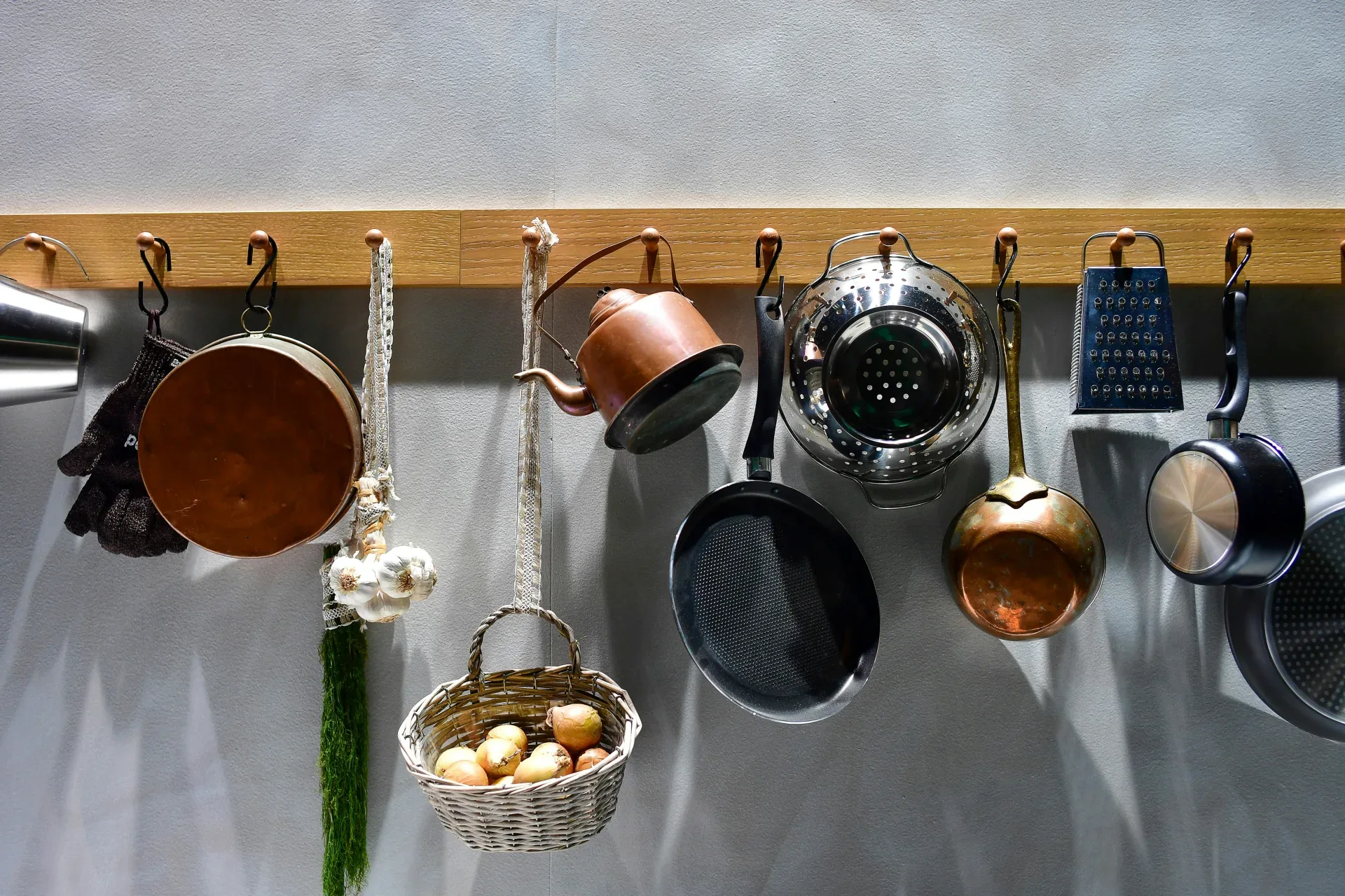 Various kitchen utensils hanging on a wooden rack.