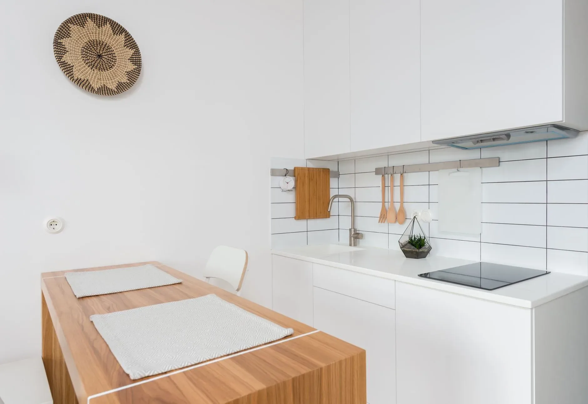 Wooden table with chairs in contemporary kitchen with white cabinets and modern appliances in daylight